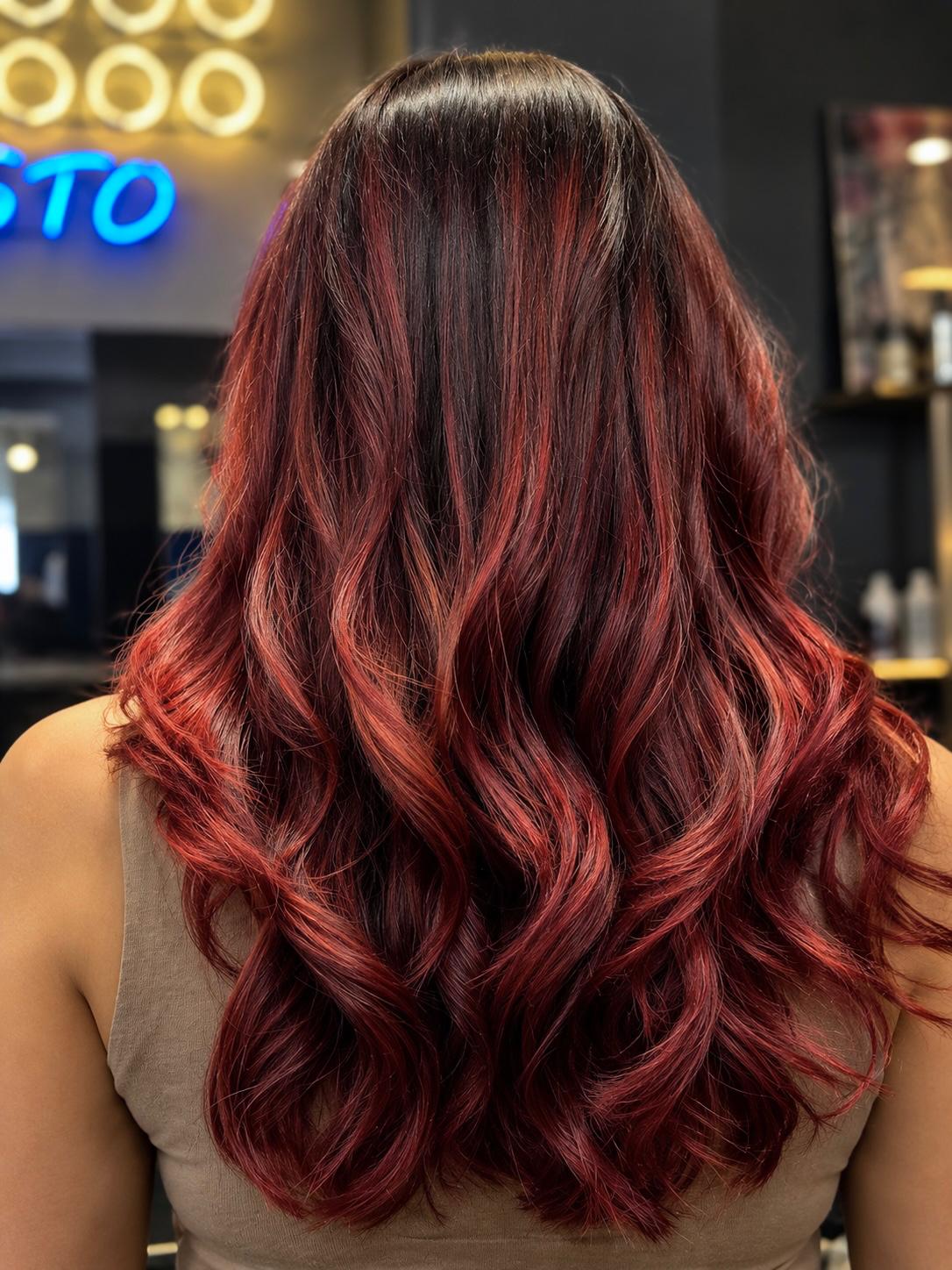 Red balayage ribbons through long dark brunette waves, seen from behind, at Gusto Hair, London