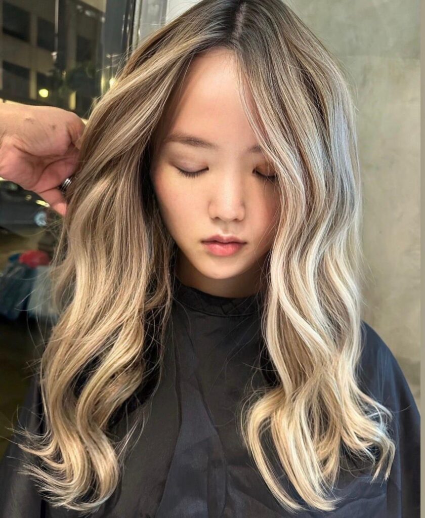 Soft beige blonde balayage on long waves with a darker root at Gusto Hair London
