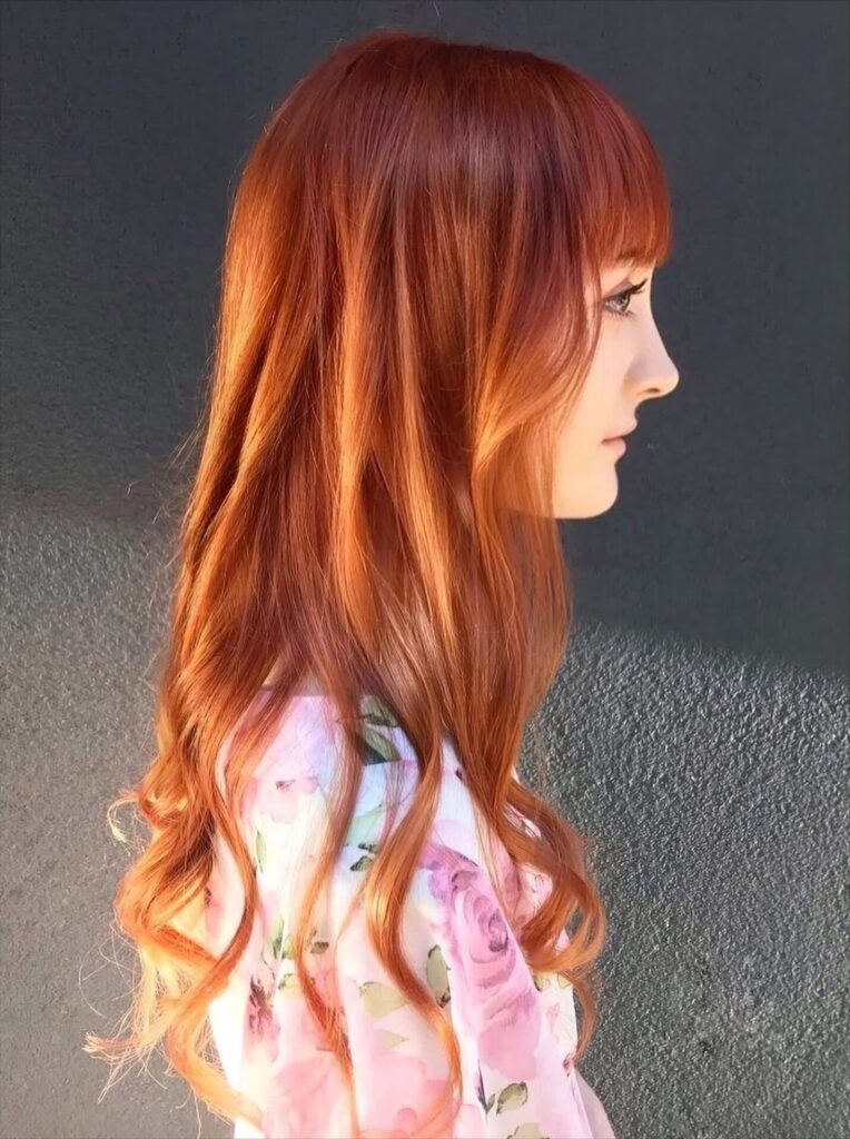 Long ginger copper hair with a full fringe, side profile, at Gusto Hair London