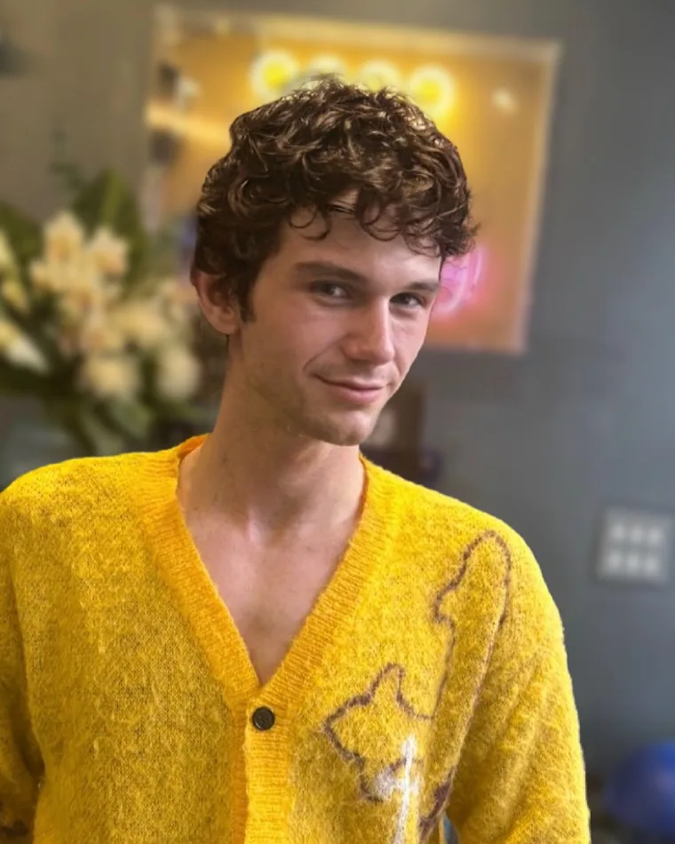 Short, reshaped curls worn with a yellow mohair cardigan