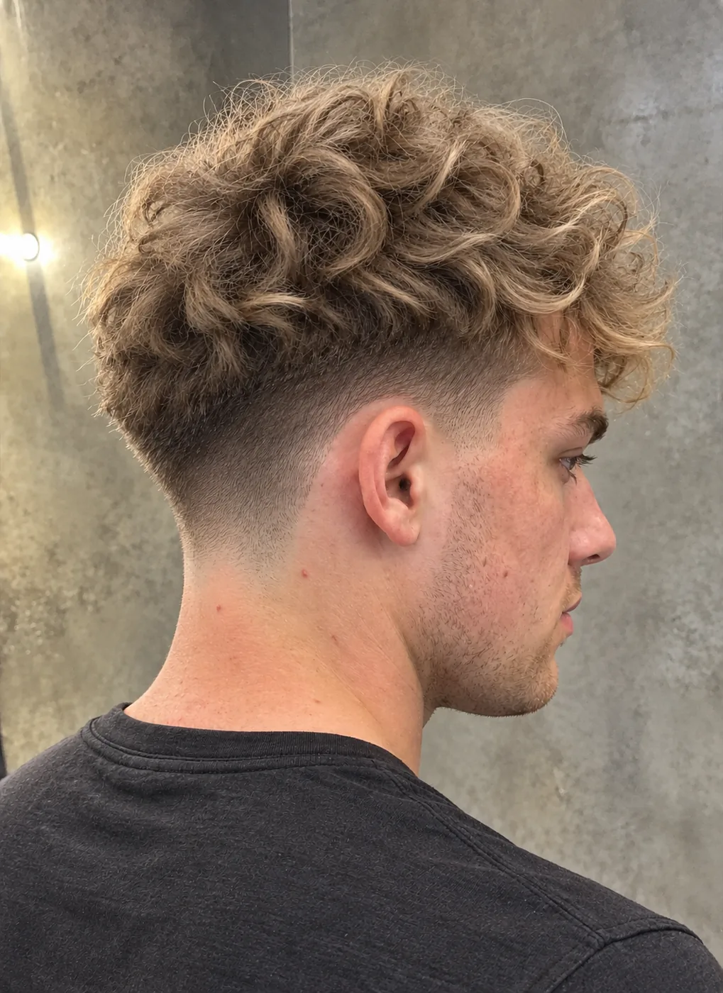 Blonde curls on top with a taper fade at the back and sides, side profile