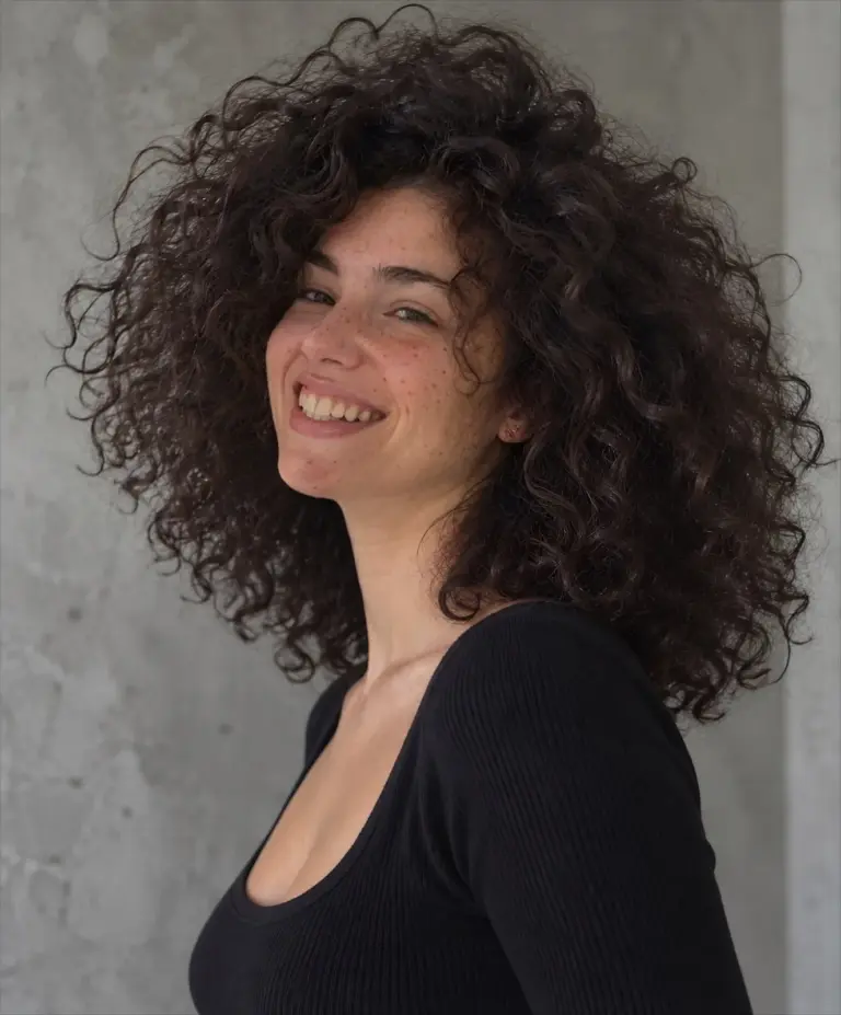 Big, bouncy curly perm on dark brunette hair, smiling client at Gusto Hair, London